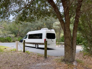 Dunnellon, FL USA - 19 Kasım 2022: ABD 'de Dunnellon, Florida yakınlarındaki Rainbow River State Park' taki bir kamp alanında beyaz Grech Kamp Van RV.