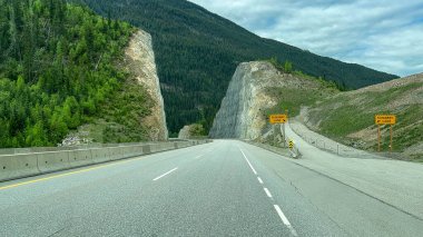Kanada 'da bulutlu bir bahar gününde Yoho, Kootenay, Banff ve Jasper Ulusal Parkı yakınlarındaki Trans Canada Otoyolu' nu sürerken manzara.