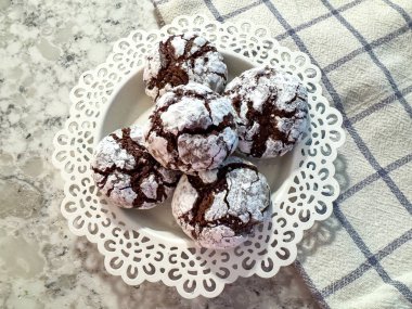 Dekoratif beyaz tabakta ev yapımı çikolatalı, kırışık kurabiyeler..