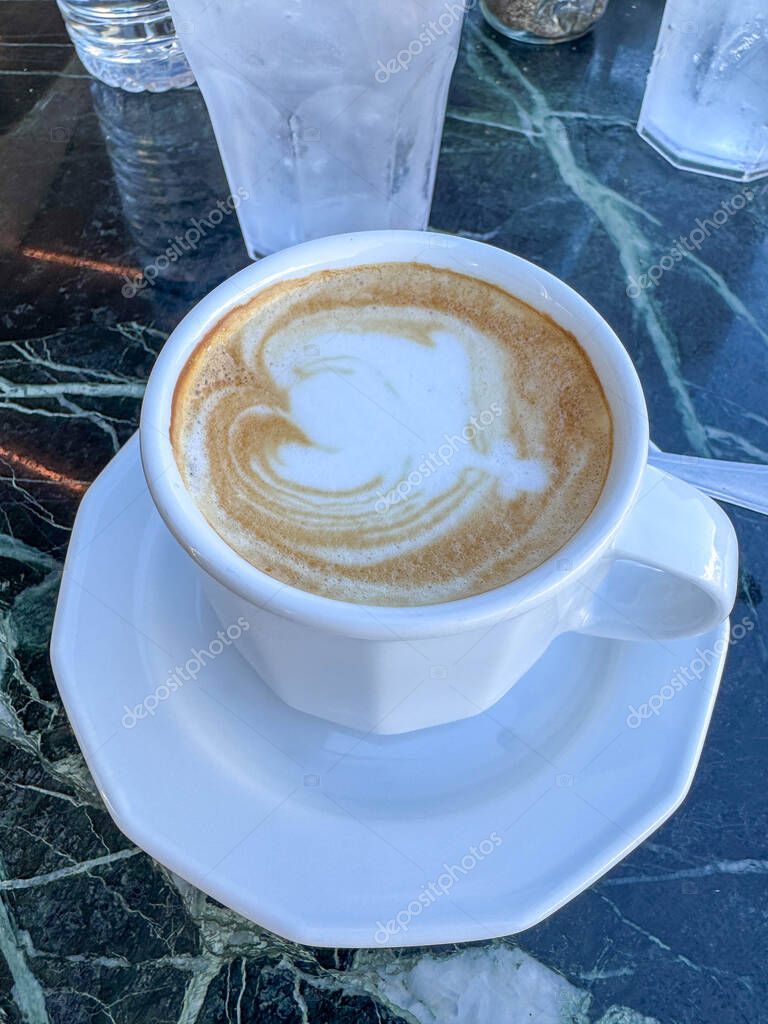 A delicous coffee latte with a foam heart in the MSC Seashore Cruise Ship Yacht Club outdoor lounge.