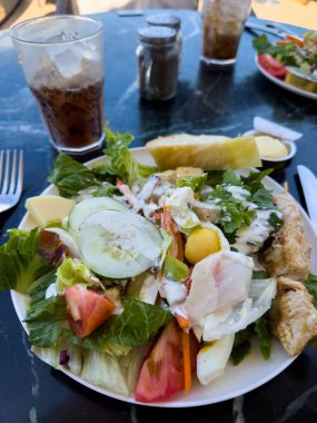 Güneşli bir günde bir yolcu gemisinde, açık bir restoranda mermer bir masada salata..