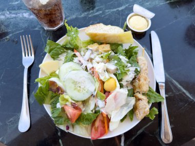 Güneşli bir günde bir yolcu gemisinde, açık bir restoranda mermer bir masada salata..