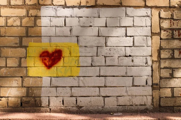 Heart on yellow brickwork background. Drawing of a heart on a background of white brickwork, a drawn sign of love.
