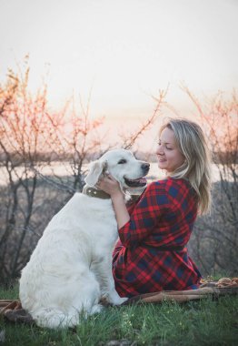 Ormanda gün batımında bir köpekle elbise giymiş güzel bir kadın..