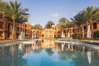 Cozy hotel with swimming pool in Africa at sunset.