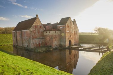 Majestic castle surrounded by a moat in Denmark at sunset.