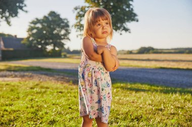 sad child in a sundress in Denmark at sunset.