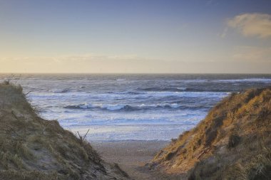 Danimarka 'da gün batımında fırtınalı kuzey denizi. Kıyı kenti Hvide Sande.