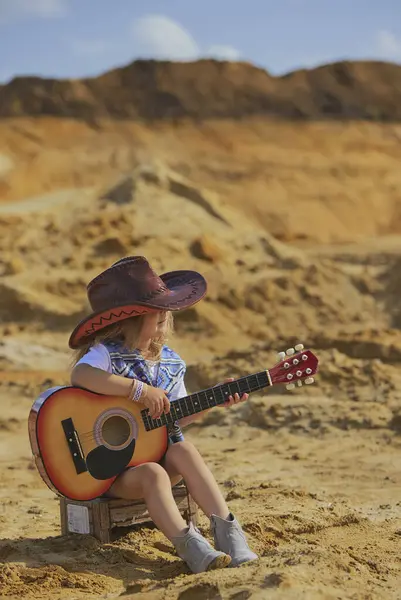 Kovboy kostümlü güzel çocuk gitar çalıyor..