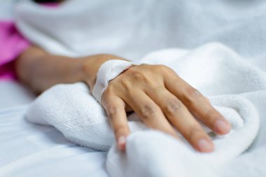 Hasta 40 'lı yaşlarda C-line' da salin damar yolu ya da yoğun bakım ünitesinde hasta yatağında hasta eli üzerinde A-hattı (Yoğun bakım ünitesi). Hastanedeki oda.