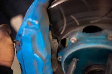 Araba tamircisi ya da tamirci araba tamirhanesinde ya da tamirhanede tamir ve onarım sorunları için disk freni ve asbest fren pedlerini kontrol ediyor.