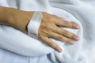 Hasta 40 'lı yaşlarda C-line' da salin damar yolu ya da yoğun bakım ünitesinde hasta yatağında hasta eli üzerinde A-hattı (Yoğun bakım ünitesi). Hastanedeki oda.