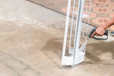 Bakım hizmeti sırasında müşteri evindeki duvardaki tozu temizlemek için havalandırma soğutucusunu suyla temizleyen işçiden işçiye.