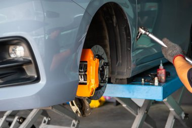 Araba tamircisi ya da tamirci araba tamirhanesinde ya da tamirhanede tamir ve onarım sorunları için disk freni ve asbest fren pedlerini kontrol ediyor.