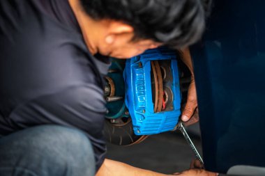 Araba tamircisi ya da tamirci araba tamirhanesinde ya da tamirhanede tamir ve onarım sorunları için disk freni ve asbest fren pedlerini kontrol ediyor.