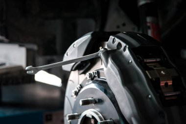 Araba tamircisi ya da tamirci araba tamirhanesinde ya da tamirhanede tamir ve onarım sorunları için disk freni ve asbest fren pedlerini kontrol ediyor.