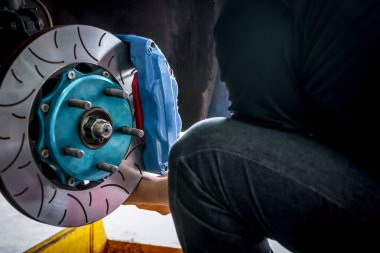 Araba tamircisi ya da tamirci araba tamirhanesinde ya da tamirhanede tamir ve onarım sorunları için disk freni ve asbest fren pedlerini kontrol ediyor.
