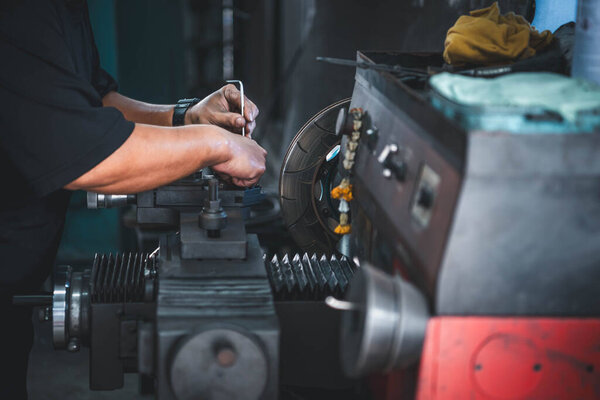 Car mechanic or serviceman disassembly and checking a disc brake and asbestos brake pads for fix and repair problem at car garage or repair shop