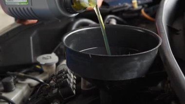 Araba tamircisi araba tamirhanesinde motor yağını boşaltıyor. Araba motorunun yağını değiştirmek için.