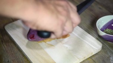 Şef marketten taze domuz kalbi pişiriyor. Mutfakta ahşap kesim tahtasıyla yemek yapıyor. Lokantada domuz kalbi var.