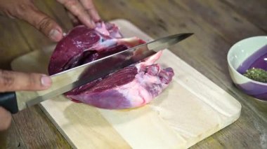 Şef marketten taze domuz kalbi pişiriyor. Mutfakta ahşap kesim tahtasıyla yemek yapıyor. Lokantada domuz kalbi var.