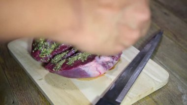 Şef marketten taze domuz kalbi pişiriyor. Mutfakta ahşap kesim tahtasıyla yemek yapıyor. Lokantada domuz kalbi var.