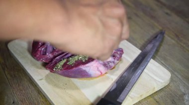 Şef marketten taze domuz kalbi pişiriyor. Mutfakta ahşap kesim tahtasıyla yemek yapıyor. Lokantada domuz kalbi var.