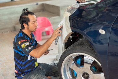 Bangkok, Tayland - 4 Nisan 2024: Otomobil tamircisi veya araba tamircisi, tamirhanedeki veya tamirhanedeki tamir ve onarım sorunları için kaporta ve fiber tampon parçalarını kontrol edin ve tamir edin