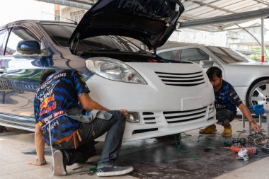 Bangkok, Tayland - 4 Nisan 2024: Otomobil tamircisi veya araba tamircisi, tamirhanedeki veya tamirhanedeki tamir ve onarım sorunları için kaporta ve fiber tampon parçalarını kontrol edin ve tamir edin
