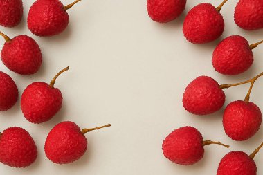 Yapay zeka, parlak su damlacıklarıyla dairesel düzenlenmiş yakut kırmızısı lychees 'in canlı bir görüntüsünü oluşturdu, dokulu pembe kabuklarını ve temiz beyaz zemine karşı taze köklerini sergiledi.