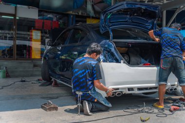 Araba tamircisi ya da tamirci tamirhanedeki ya da tamirhanedeki tamir ve onarım problemleri için kaporta ve fiber tampon parçalarını kontrol edip onarıyor.