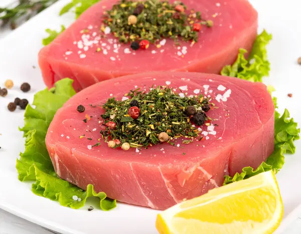 Yapay zeka kömürün üzerinde ızgara yapılmış hafif dumanla mükemmel kurutulmuş ton balıklı bifteğin en üst görüntüsünü oluşturdu. Tuz ve karabiber ile tatlandırılmış, taze biberiye ve limon dilimleriyle süslenmiş..