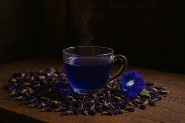 Yapay zeka, ahşap bir masada, temiz bir cam fincanda sıcak kelebek bezelye çayının görüntüsünü oluşturdu. Kurumuş ve taze yapraklar, kaliteli eczacı arka planı zengin renk ve sakin atmosfer.