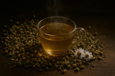 Yapay zeka, koyu ahşap bir masa üzerinde koyu renkli, taze çiçeklerle çevrili, sıcak papatya çayıyla birlikte temiz bir cam bardak görüntüsü oluşturdu.