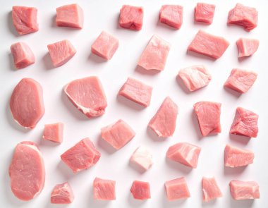 Yapay zeka, temiz beyaz arka planda çeşitli parçalardan kesilmiş taze çiğ domuz eti parçalarının üst görüntüsünü oluşturdu.
