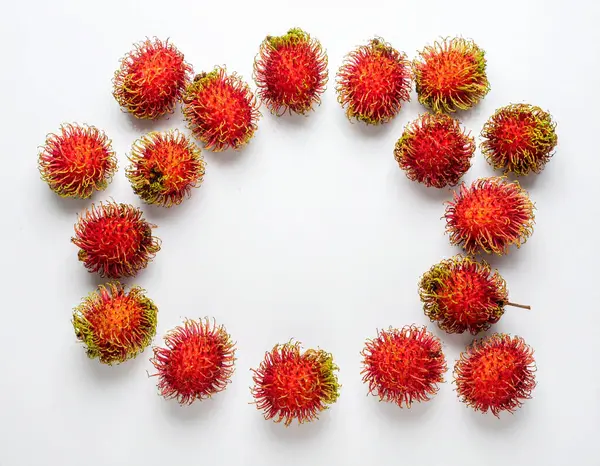 Yapay zeka, parlak su damlacıklarıyla dairesel düzenlenmiş yakut kırmızısı rambutanların parlak görüntüsünü oluşturdu. Kıllı dikenlerini ve taze köklerini temiz beyaz arka planda sergilediler.