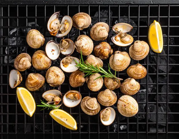 Yapay zeka kömürün üzerinde ızgara yapılmış taze tatlı istiridye manzarası oluşturdu, dumanlı aroma ve sulu etle mükemmel pişirildi. Biberiye ve limon dilimleriyle süslenmiş tuzlu ve karabiberli..