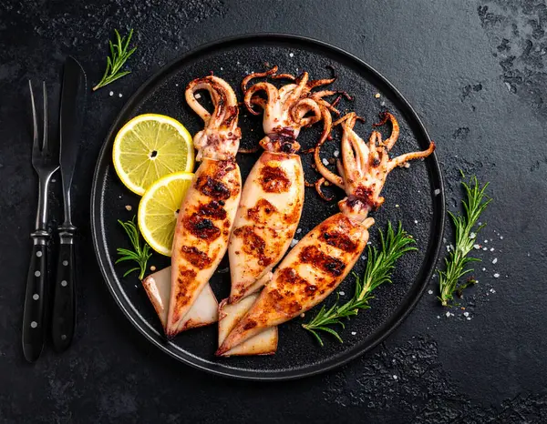 Yapay zeka kömürün üzerinde ızgara yapılmış taze ve enfes kalamar manzarası oluşturdu. Yumuşak dokular ve dumanlı aromayla mükemmel pişirildi. Biberiyeli limon dilimleriyle süslenmiş tuzlu ve karabiberli..