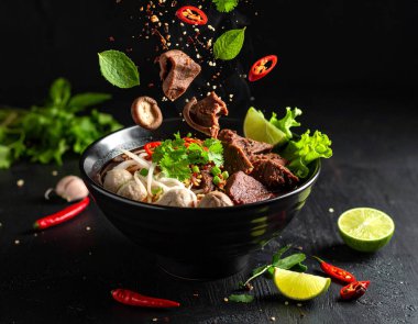 Taze malzemelerle dolu zengin Tayland teknesi eriştesi üretti. Süslü Tayland kâsesine düştü. Koyu aromatik et suyu çorbası, domuz kanı, pirinç, otantik sokak yemekleri.