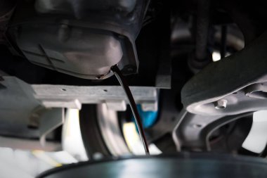 Araba tamircisi araba tamirhanesinde motor yağını boşaltıyor. Araba motorunun yağını değiştirmek için.