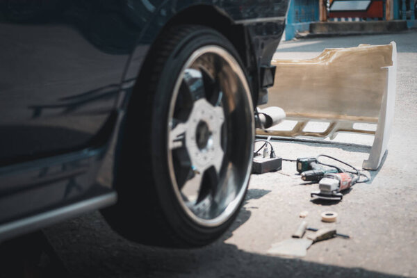 Denter or car mechanic serviceman check and fix body work and fiber bumper body part for fix and repair problem at car garage or repair shop