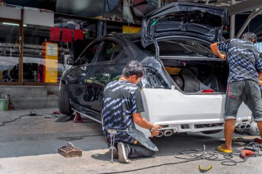 Araba tamircisi ya da tamirci tamirhanedeki ya da tamirhanedeki tamir ve onarım problemleri için kaporta ve fiber tampon parçalarını kontrol edip onarıyor.