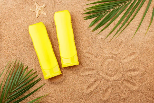 stock image Summer background. Sunscreens and palm leaves on the sand on the beach. Top view. 