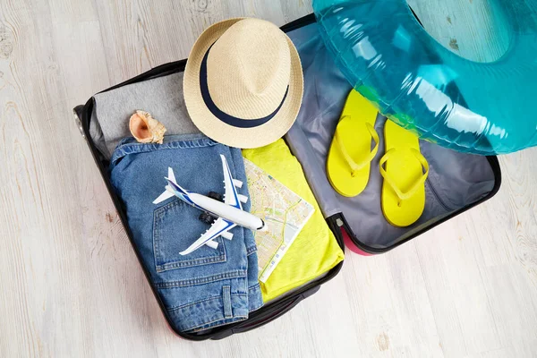 An open suitcase with clothes and accessories for a seaside vacation. Summer travel, preparation for the trip, packing of luggage.