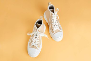 İzole edilmiş turuncu arka planda bir çift bej spor ayakkabı. Koşu ayakkabıları. 