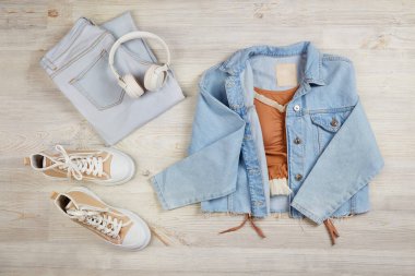 Mavi kot ceket, kot pantolon ve spor ayakkabı. Mevsimlik sonbahar ya da yaz modasına uygun kadın kıyafetleri. Üst görünüm. 