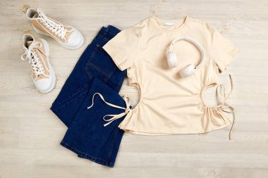 Bej tişört, kot pantolon ve spor ayakkabı. Kadınlar günlük kıyafet giyer. Üst görünüm.