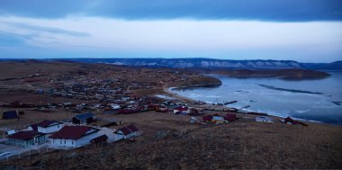 The village of Sakhyurt on the shore of Lake Baikal in the morning. The frozen bay of the lake at the beginning of winter. Panorama clipart