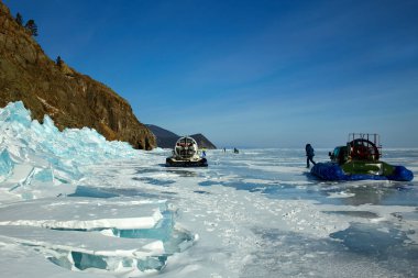 Donmuş Baykal Gölü 'nün şeffaf buzunda turistleri taşımak için bir hovercraft. Kış gezisi. Büyük, şeffaf mavi buz blokları, hummolar.. 