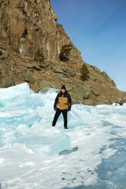 A man stands by a huge pile of ice on the frozen Lake Baikal. Winter trip. Vertical orientation clipart